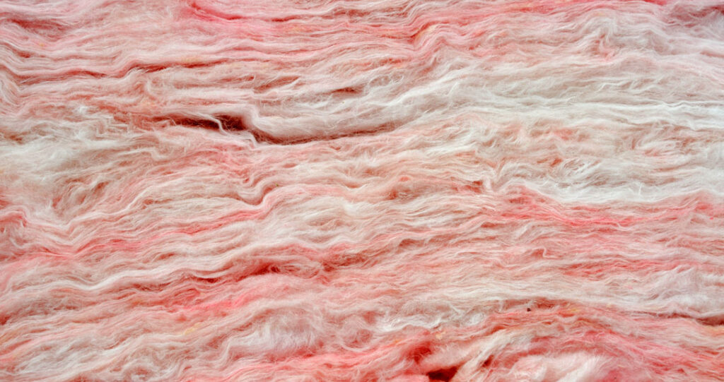 Close-up view of textured pink insulation material with wavy patterns and a mix of light and dark pink hues.