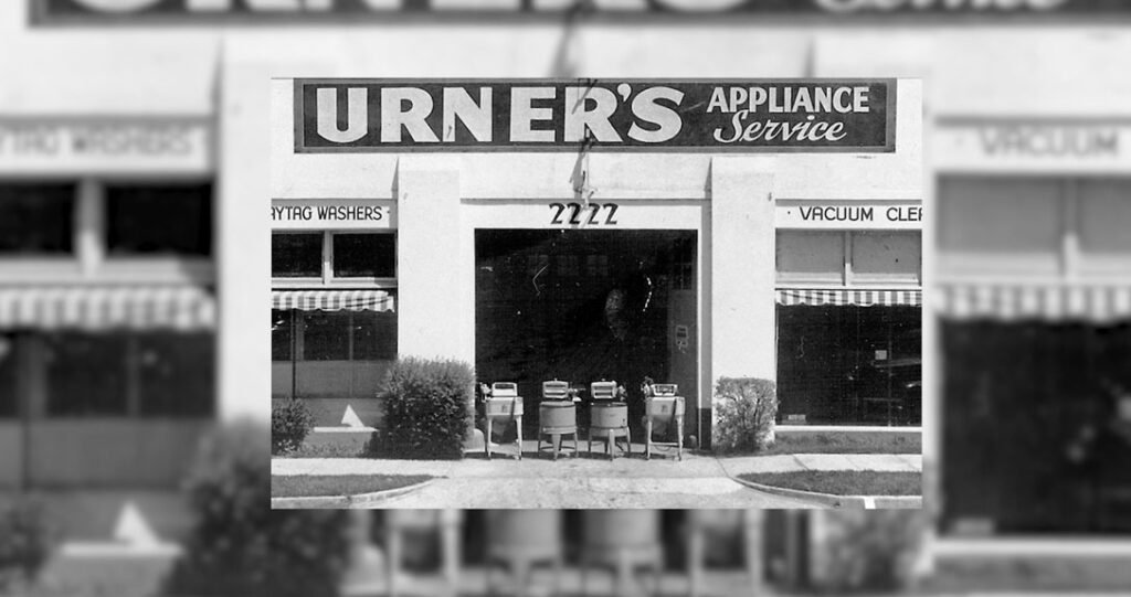 Black and white photo of urner's appliance service storefront with vacuum cleaners displayed in the window under the store sign. address number 2222 prominently shown.