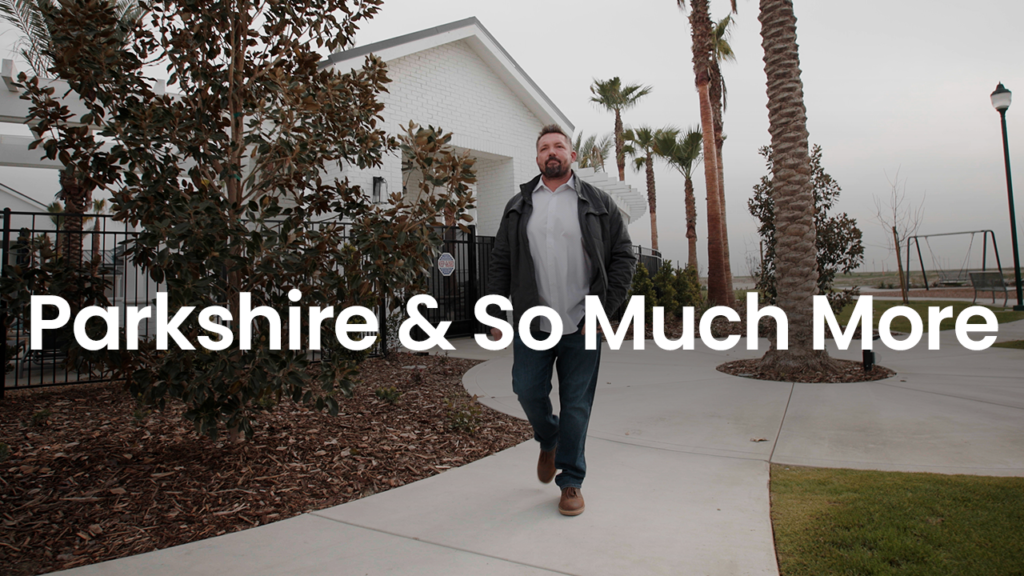A man walking confidently along a paved path in a park-like setting with trees and palms, under a cloudy sky. overlay text reads "parkshire & so much more".