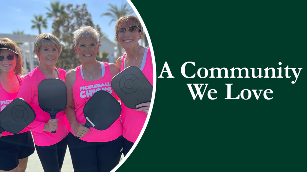 Four smiling women in pink tops, holding pickleball paddles, stand together outdoors under a sunny sky, with text "a community we love".