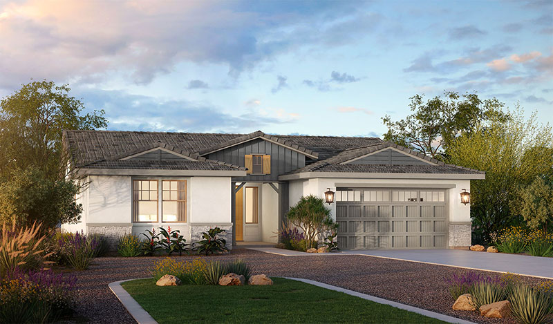 Modern single-story house with a gray garage door, white exterior walls, and landscaped front yard featuring rocks, shrubs, and flowers. The driveway is gravel, and the home is surrounded by trees under a partly cloudy sky.